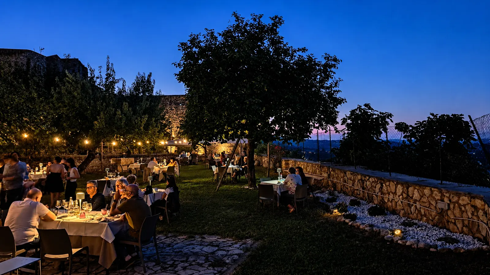 Cena nel giardino panoramico del ristoro Hortus 74 con le luci accese al tramonto